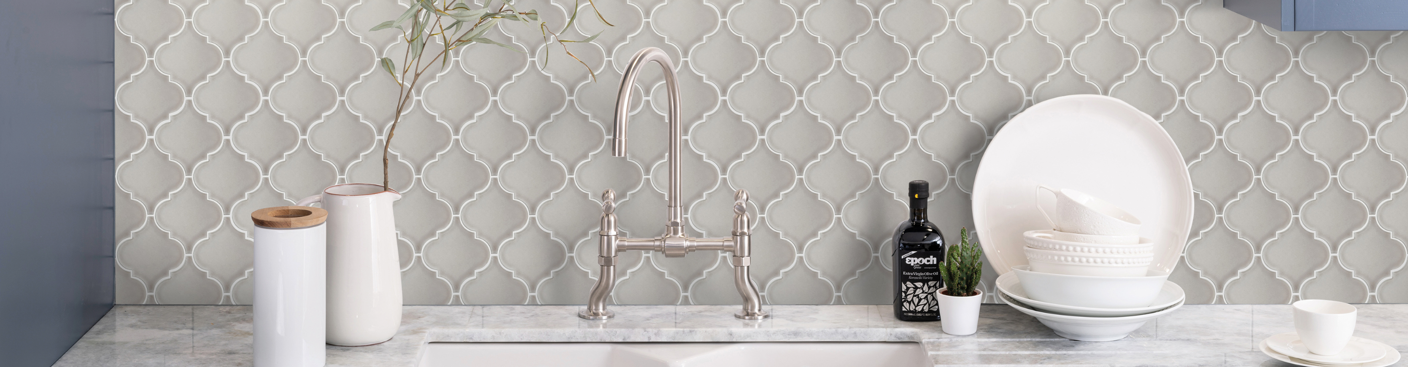 grey tile backsplash geometric shape tile, moroccan tile in kitchen with white ceramic apron sink and blue cabinets